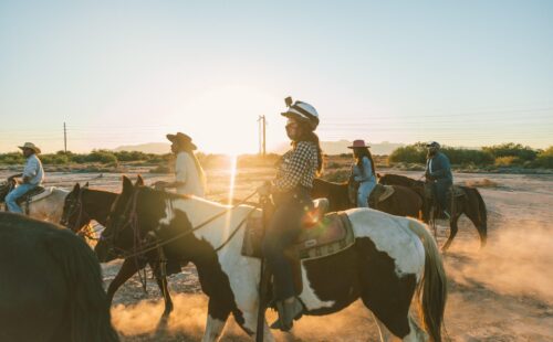 A woman riding a horse with a group of people on a horse behind her